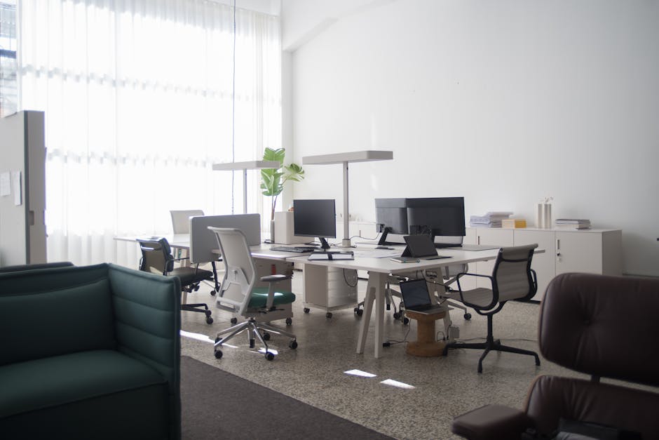 A spacious office interior in Portugal with desks, chairs, and computers under natural light.